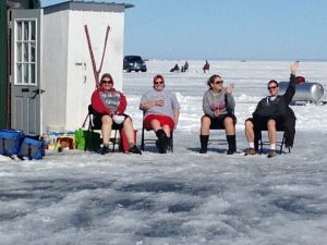 four people sit outside on frozen lake