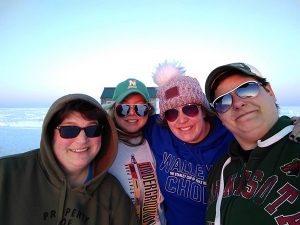 four women pose ice fishing