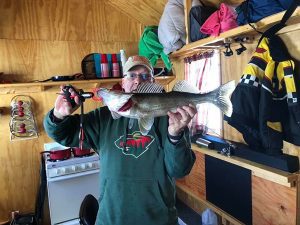 man in green sweatshirt holds caught fish